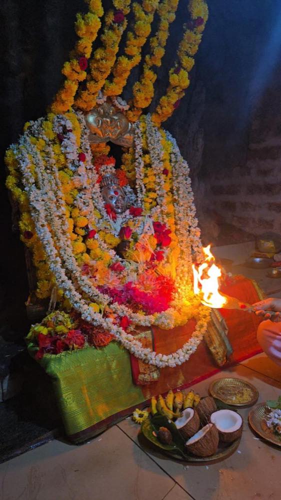 Aarti lamp held before a garlanded deity