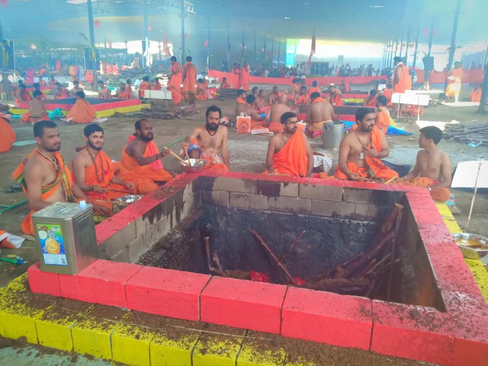 A large gathering of priests at a brick fire pit